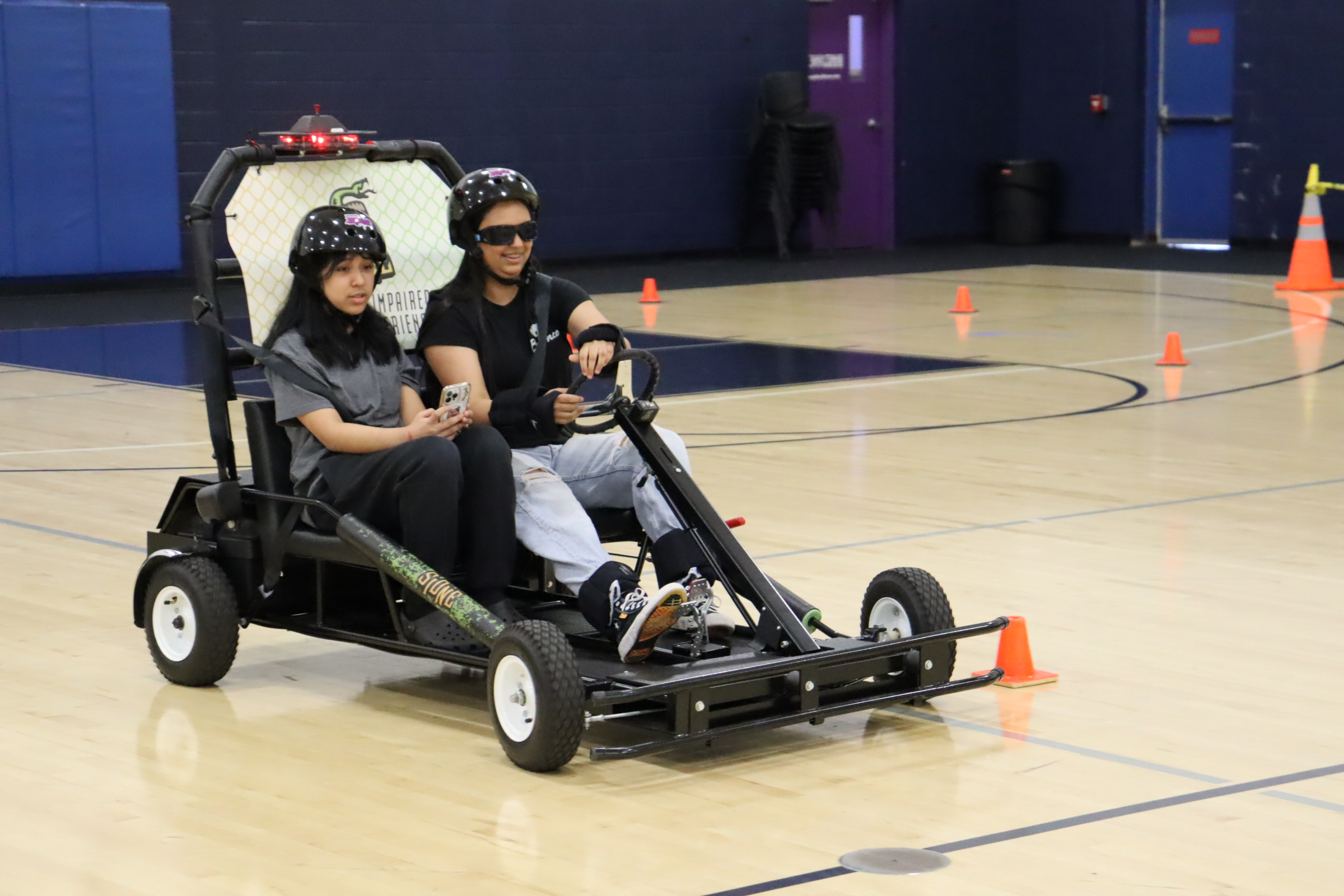 Two people riding in a cart during the Fatal Vision driving simulation.